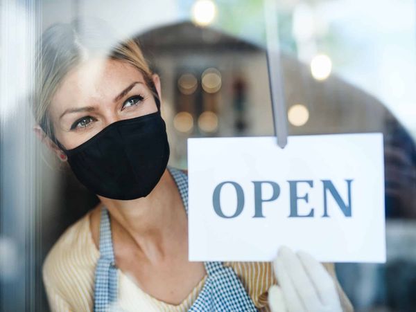 Coffee shop woman owner with face mask, open after lockdown quarantine