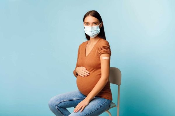 Vaccinated Pregnant Woman Showing Arm After Vaccine Injection, Blue Background