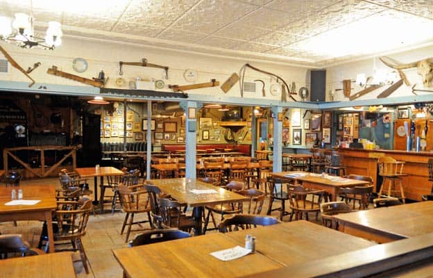 The walls are covered with historic photos, rustic tools, and old instruments, which give the bar its unique charm.
