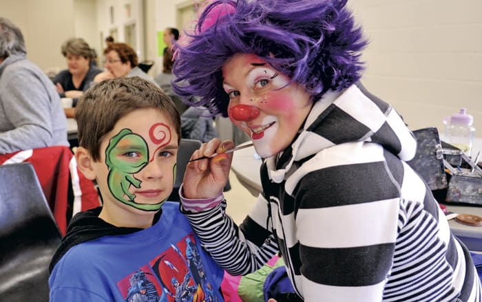 Connor Niven, 7, gets a green lizard painted on his face by Kricket and Krew at Linwood Snofest on Saturday afternoon. The day started with a hearty breakfast served up by local firefighters, and the ever-popular sno-pitch tournament.[Liz Bevan / The Observer]
