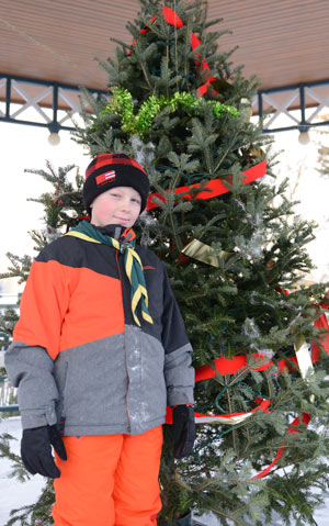 Scout Zain Wilson stands in front a decorated Christmas tree at the bandstand in Elmira’s Gore Park, where the 1st Elmira Scouts are selling Christmas Trees once again for their annual fundraiser.